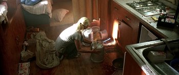 Movie still from “The Hills Have Eyes” (2006), directed by Alexandre Aja – A woman kneeling on the floor in front of a stove; Medium shot, High angle