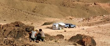 Movie still from “The Hills Have Eyes” (2006), directed by Alexandre Aja – A couple of people sitting on the side of a dirt road; Extreme Wide shot, High angle