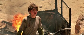 Movie still from “The Hills Have Eyes” (2006), directed by Alexandre Aja – A young boy is standing in front of a pile of rubble; Medium shot, Over the shoulder angle