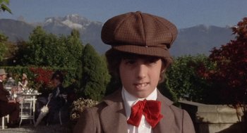 Movie still from “Daisy Miller” (1974), directed by Peter Bogdanovich – A young boy wearing a hat and a bow tie; Close Up shot, High angle