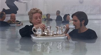 Movie still from “Daisy Miller” (1974), directed by Peter Bogdanovich – Two people sitting at a table with a tray of tea; Wide shot, High angle