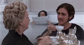 Movie still from “Daisy Miller” (1974), directed by Peter Bogdanovich – A man and a woman sitting at a table drinking coffee; Medium shot, Over the shoulder angle