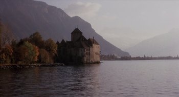Movie still from “Daisy Miller” (1974), directed by Peter Bogdanovich – An old castle on the water with mountains in the background; Extreme Wide shot, Low angle
