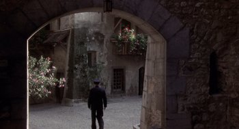 Movie still from “Daisy Miller” (1974), directed by Peter Bogdanovich – A man standing in the middle of an arched courtyard; Extreme Wide shot, High angle