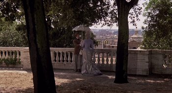 Movie still from “Daisy Miller” (1974), directed by Peter Bogdanovich – A man and a woman standing under an umbrella; Wide shot, Over the shoulder angle