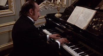 Movie still from “Daisy Miller” (1974), directed by Peter Bogdanovich – A man in a suit playing a piano; Medium shot, High angle