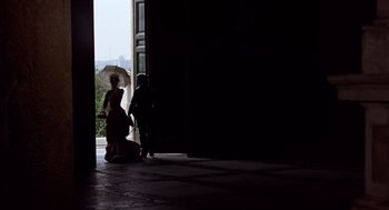 Movie still from “Daisy Miller” (1974), directed by Peter Bogdanovich – A woman and a man are standing in front of an open door; Extreme Wide shot, Low angle