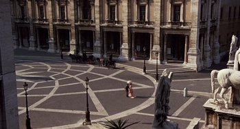 Movie still from “Daisy Miller” (1974), directed by Peter Bogdanovich – An empty courtyard with a statue of a woman in a black dress; Extreme Wide shot, High angle