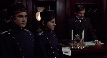 Movie still from “Daisy Miller” (1974), directed by Peter Bogdanovich – A group of people standing next to each other in a room; Medium shot, Over the shoulder angle