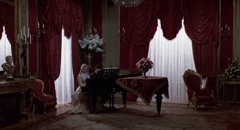 Movie still from “Daisy Miller” (1974), directed by Peter Bogdanovich – Two people are sitting at a piano in a living room; Wide shot, High angle