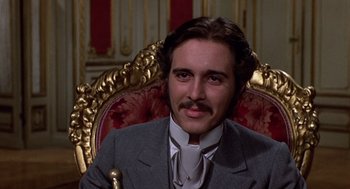 Movie still from “Daisy Miller” (1974), directed by Peter Bogdanovich – A man sitting in a chair wearing a suit and tie; Close Up shot, Low angle
