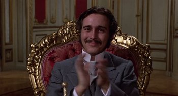 Movie still from “Daisy Miller” (1974), directed by Peter Bogdanovich – A man sitting in a chair clapping his hands; Close Up shot, Low angle