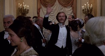 Movie still from “Daisy Miller” (1974), directed by Peter Bogdanovich – A man in a tuxedo waving at a party; Medium shot, Low angle