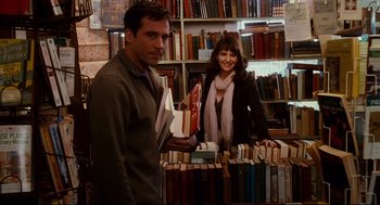 Movie still from “Dan in Real Life” (2007), directed by Peter Hedges – A man and a woman standing in front of books; Medium shot, High angle