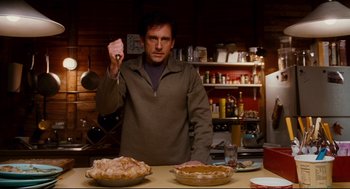 Movie still from “Dan in Real Life” (2007), directed by Peter Hedges – A man standing in front of a table holding a knife; Medium shot, Over the shoulder angle