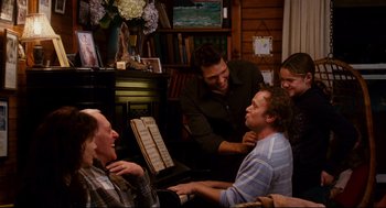 Movie still from “Dan in Real Life” (2007), directed by Peter Hedges – A group of people sitting around a piano together; Medium shot, Over the shoulder angle