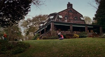 Movie still from “Dan in Real Life” (2007), directed by Peter Hedges – Two people sitting on the grass in front of a house; Extreme Wide shot, Low angle