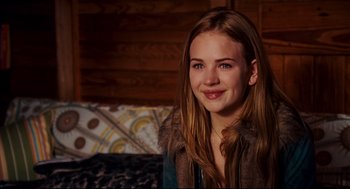 Movie still from “Dan in Real Life” (2007), directed by Peter Hedges – A young woman smiling for the camera in front of a wooden wall; Close Up shot, Over the shoulder angle