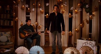 Movie still from “Dan in Real Life” (2007), directed by Peter Hedges – A man standing in front of a man playing a guitar; Wide shot, Over the shoulder angle