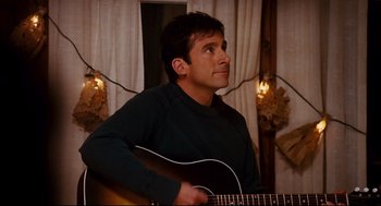 Movie still from “Dan in Real Life” (2007), directed by Peter Hedges – A man is playing a guitar in a room; Medium shot, Over the shoulder angle
