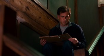 Movie still from “Dan in Real Life” (2007), directed by Peter Hedges – A man sitting on the ground reading a book; Medium shot, Low angle