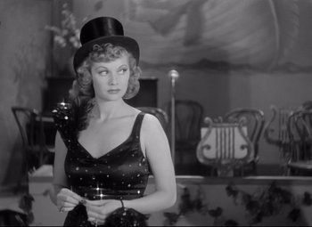 Movie still from “Dance, Girl, Dance” (1940), directed by Roy Del Ruth – A woman wearing a top hat and holding a microphone; Medium shot, Over the shoulder angle