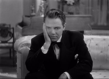 Movie still from “Dance, Girl, Dance” (1940), directed by Roy Del Ruth – A black and white photo of a man sitting on a couch; Close Up shot, High angle
