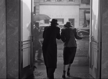 Movie still from “Dance, Girl, Dance” (1940), directed by Roy Del Ruth – Two women walking down a street with an umbrella; Wide shot, Low angle