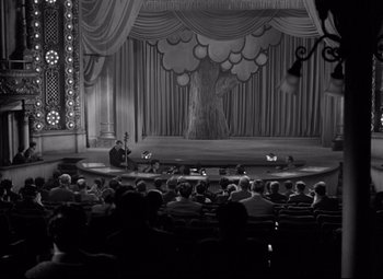 Movie still from “Dance, Girl, Dance” (1940), directed by Roy Del Ruth – An audience is sitting in front of a stage with a man on it; Extreme Wide shot, High angle