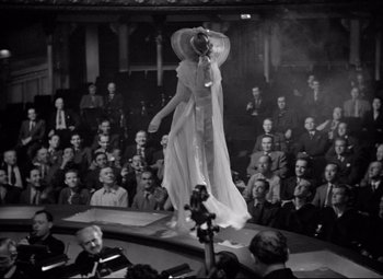 Movie still from “Dance, Girl, Dance” (1940), directed by Roy Del Ruth – A woman in a white dress on a stage; Wide shot, High angle