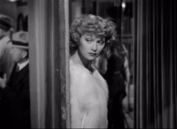 Movie still from “Dance, Girl, Dance” (1940), directed by Roy Del Ruth – A black and white photo of a woman in a fur coat; Medium shot, High angle