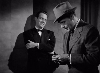 Movie still from “Dance, Girl, Dance” (1940), directed by Roy Del Ruth – A man in a suit and a man in a hat looking at a cell phone; Medium shot, Low angle