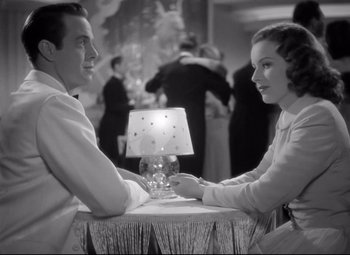 Movie still from “Dance, Girl, Dance” (1940), directed by Roy Del Ruth – A man and a woman sitting at a table with a lamp; Medium shot, Low angle