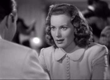 Movie still from “Dance, Girl, Dance” (1940), directed by Roy Del Ruth – A black - and - white photo of a woman in a white dress; Close Up shot, Over the shoulder angle