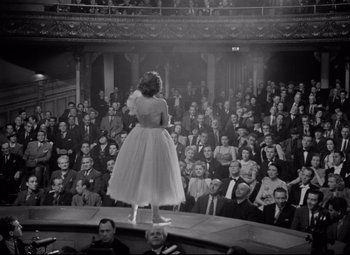 Movie still from “Dance, Girl, Dance” (1940), directed by Roy Del Ruth – A woman standing on a stage in front of an audience; Wide shot, High angle