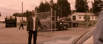 Movie still from “Dancer in the Dark” (2000), directed by Lars von Trier – A man standing in front of a car in a parking lot; Wide shot, Over the shoulder angle