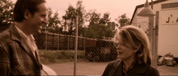 Movie still from “Dancer in the Dark” (2000), directed by Lars von Trier – A woman standing in front of a chain link fence; Close Up shot, Over the shoulder angle