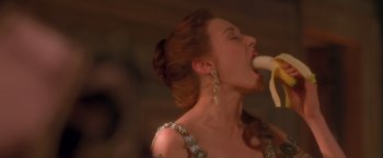 Movie still from “Dangerous Beauty” (1998), directed by Marshall Herskovitz – A woman in a dress is holding a banana in her mouth; Close Up shot, Low angle