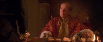 Movie still from “Dangerous Beauty” (1998), directed by Marshall Herskovitz – A man sitting at a table in front of papers; Close Up shot, Over the shoulder angle