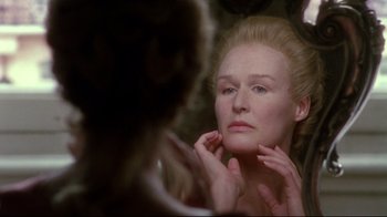 Movie still from “Dangerous Liaisons” (1988), directed by Stephen Frears – A woman looking in the mirror while holding her hand to her face; Close Up shot, Over the shoulder angle