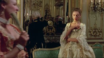 Movie still from “Dangerous Liaisons” (1988), directed by Stephen Frears – A woman in a dress standing in front of a mirror in a room; Medium shot, Over the shoulder angle