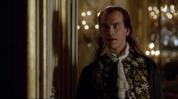 Movie still from “Dangerous Liaisons” (1988), directed by Stephen Frears – A man with long black hair wearing a black and gold jacket; Close Up shot, Over the shoulder angle