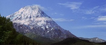 Movie still from “Dante's Peak” (1997), directed by Roger Donaldson – A mountain with snow on it's side and clouds in the sky; Extreme Wide shot, Low angle