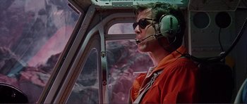 Movie still from “Dante's Peak” (1997), directed by Roger Donaldson – A man wearing a red jacket is in the cockpit of a helicopter; Medium shot, Low angle