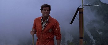 Movie still from “Dante's Peak” (1997), directed by Roger Donaldson – A man in an orange jumpsuit holding a stick; Medium shot, Low angle