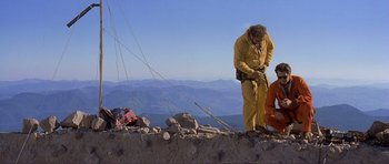 Movie still from “Dante's Peak” (1997), directed by Roger Donaldson – Two men in yellow suits standing on a hill; Wide shot, Low angle