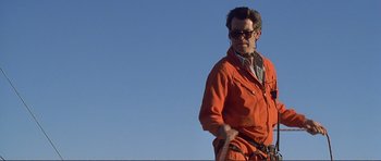 Movie still from “Dante's Peak” (1997), directed by Roger Donaldson – A man in an orange jacket is standing outside; Medium shot, Low angle