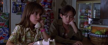 Movie still from “Dante's Peak” (1997), directed by Roger Donaldson – A couple of people sitting at a table with a phone; Close Up shot, Low angle