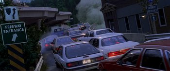 Movie still from “Dante's Peak” (1997), directed by Roger Donaldson – A street filled with lots of traffic with smoke billowing out of it; Extreme Wide shot, High angle