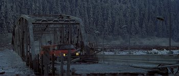 Movie still from “Dante's Peak” (1997), directed by Roger Donaldson – A red car is parked on the side of a bridge; Extreme Wide shot, High angle